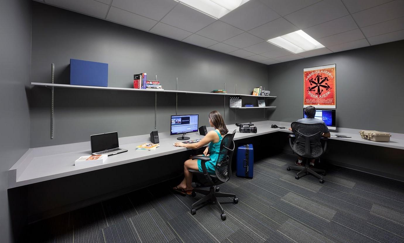 two students work at computers in the media studies editing room